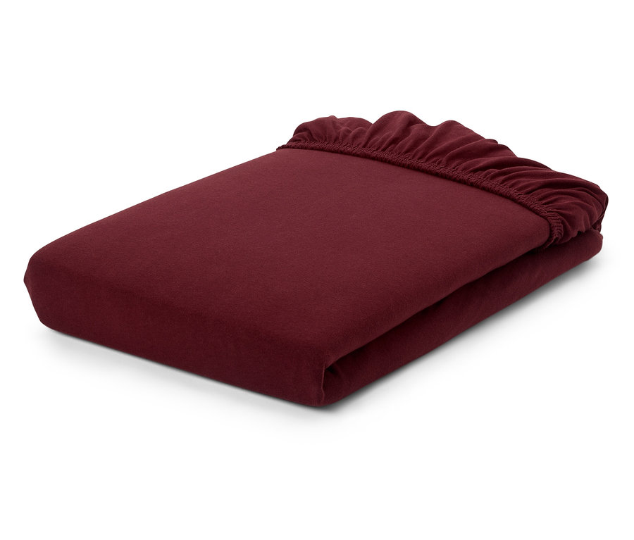 Un drap-housse bordeaux plié sur un fond blanc.