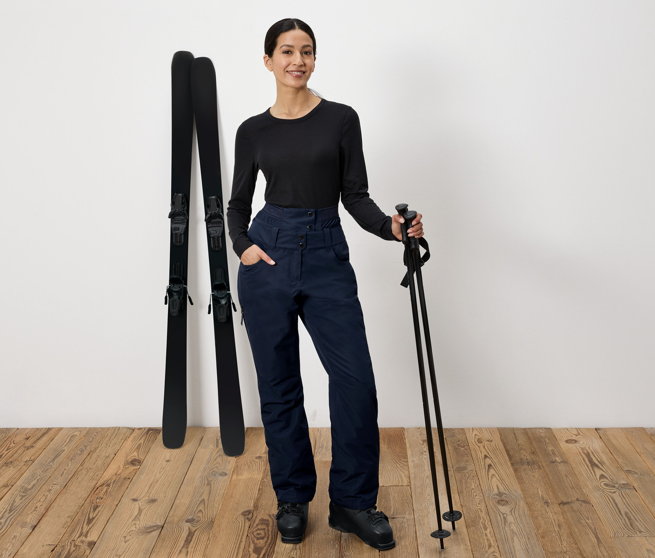 Une femme pose avec des bâtons de ski et des skis.