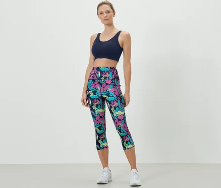 Une femme porte un soutien-gorge de sport et un collant de sport 3/4 avec un imprimé intégral.