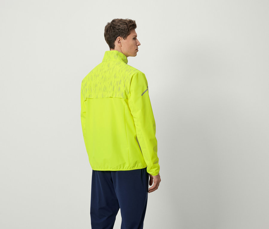 Un homme portant une veste de course jaune néon et un pantalon bleu marine, dos à la caméra.