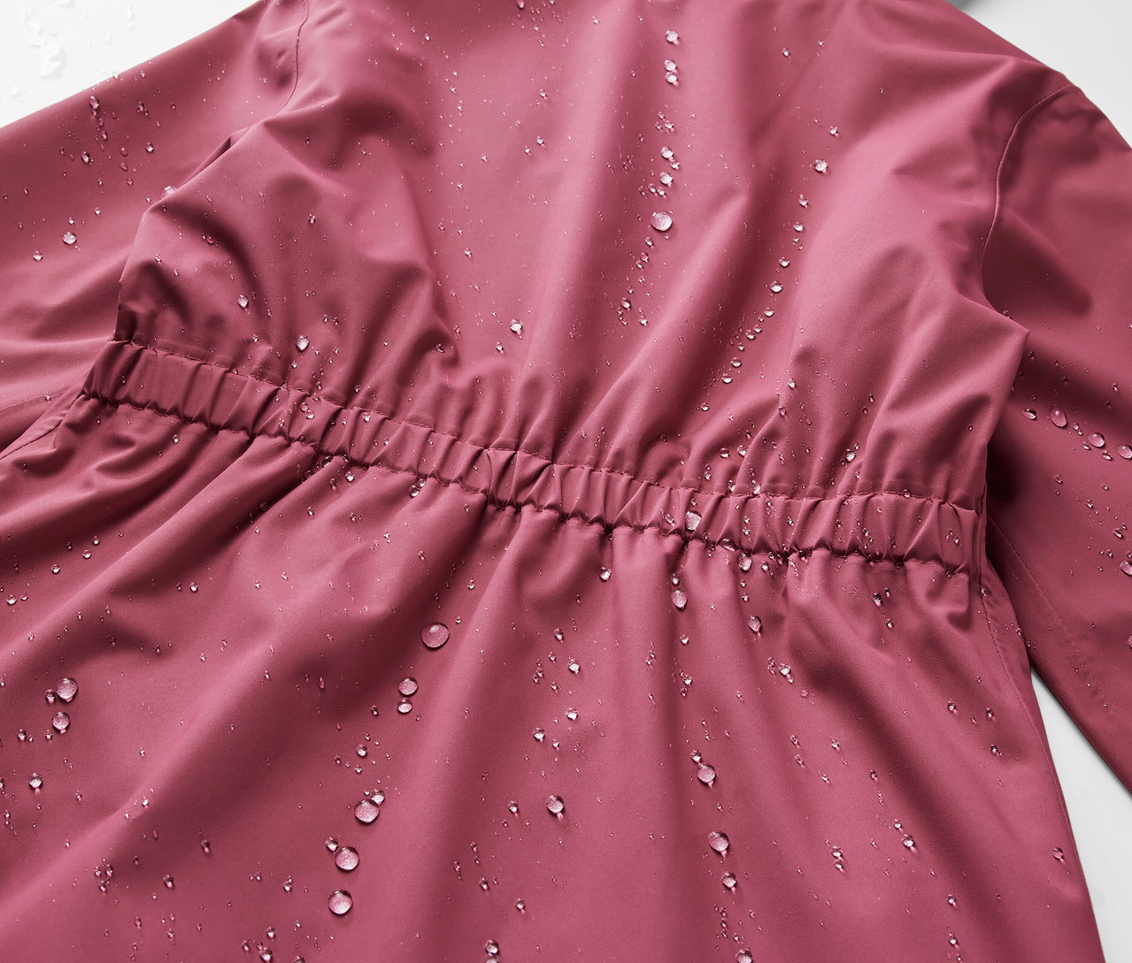Gros plan sur l'arrière d'une parka de pluie pour enfant avec des gouttes d'eau.