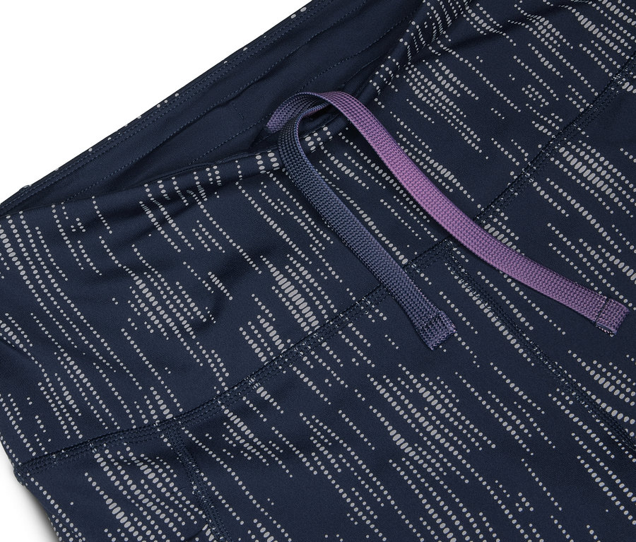 Gros plan sur un short de sport bleu marine avec un motif argenté et un cordon de serrage violet et bleu.