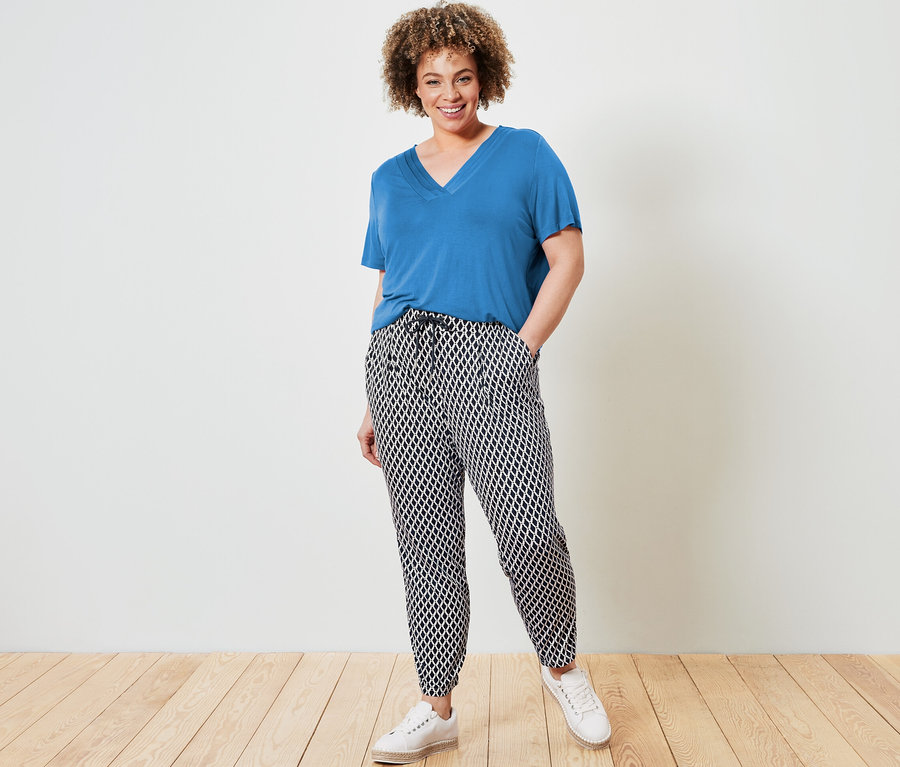 Femme posant en t-shirt bleu cobalt avec soufflet et pantalon en jersey imprimé.