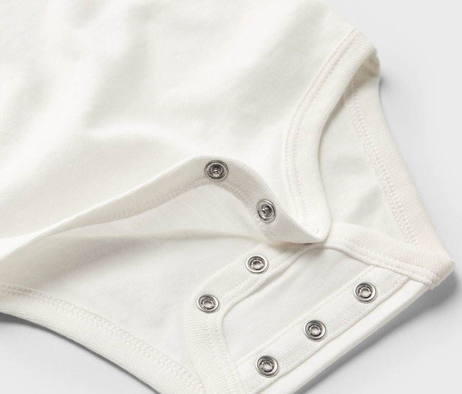 Gros plan sur un body blanc évolutif pour bébé avec des boutons-pression.
