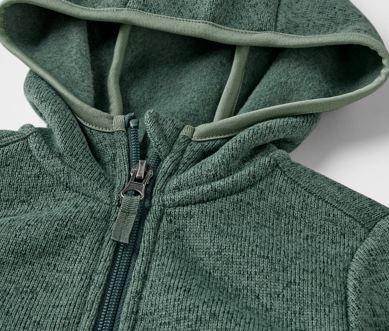 Gros plan sur une veste en maille polaire pour enfant avec fermeture éclair et capuche.