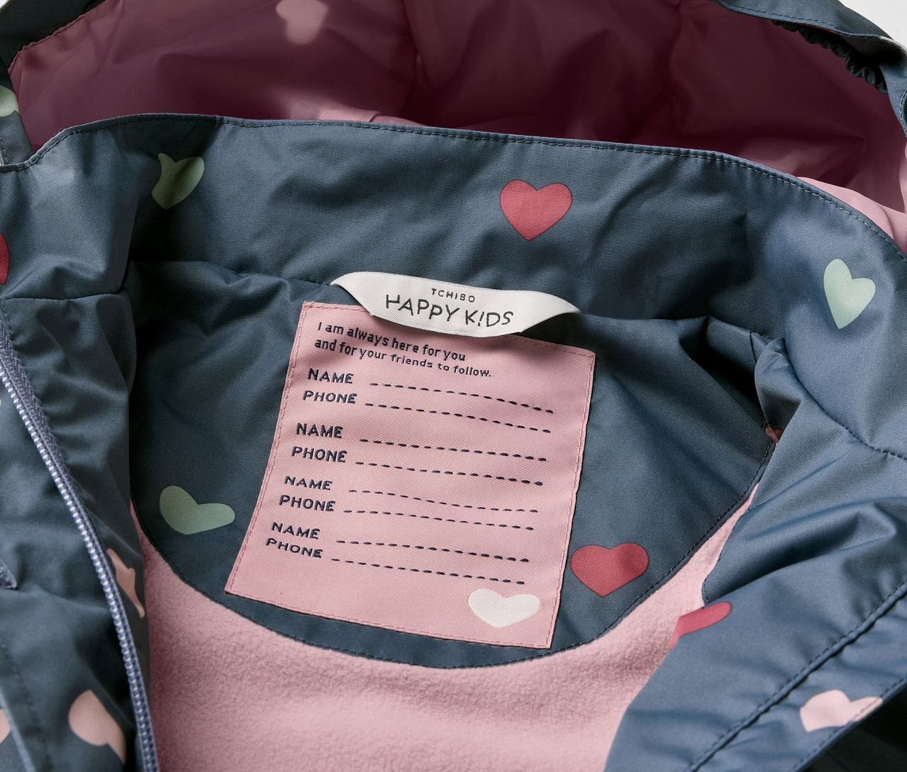 Gros plan sur une veste imperméable thermique pour enfants avec des motifs de cœurs.