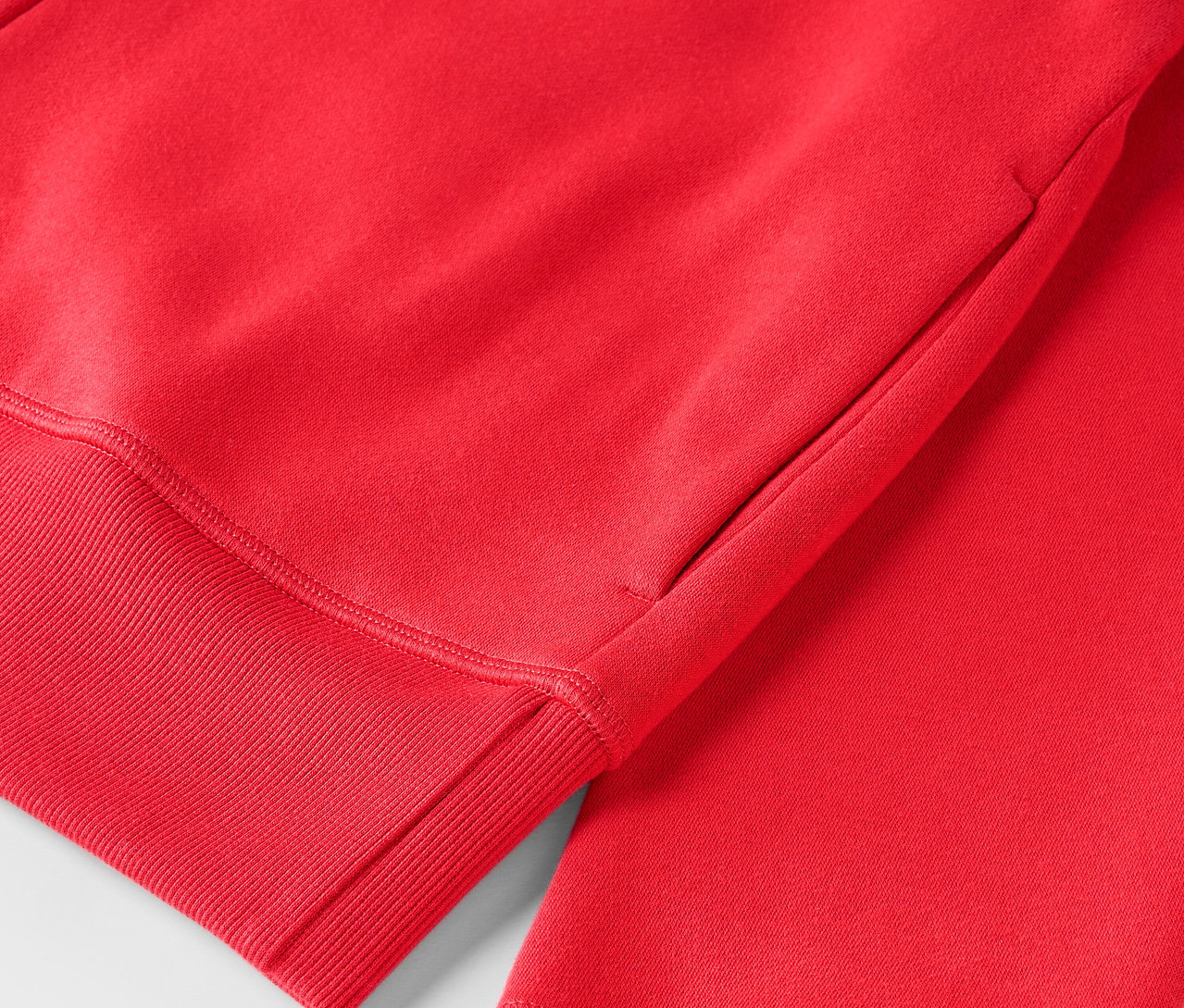Gros plan sur un sweat à capuche rouge avec ourlet côtelé.