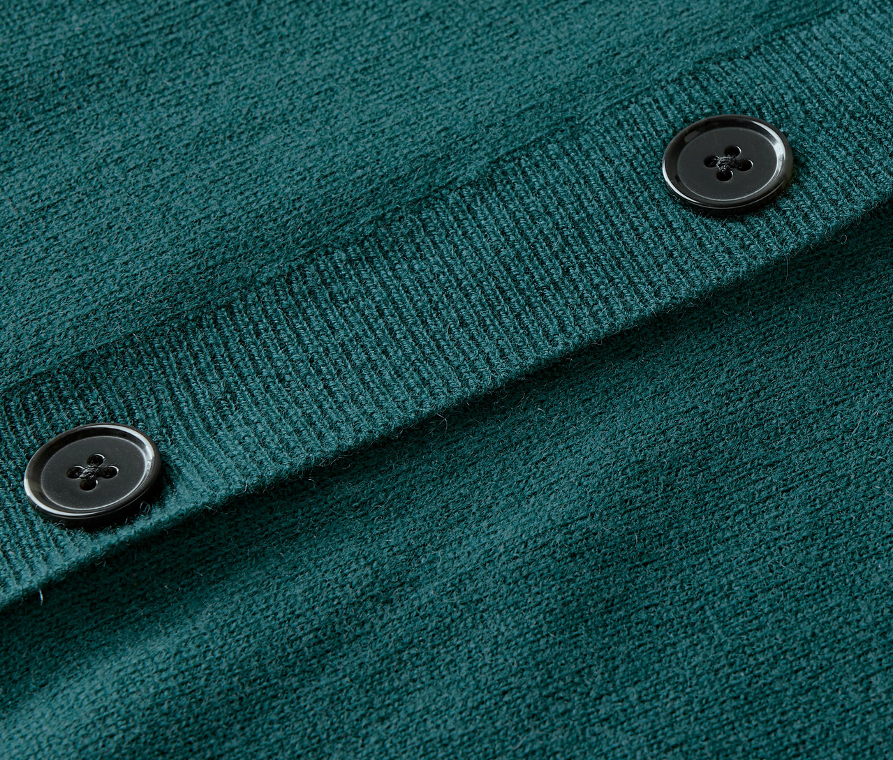 Gros plan sur un cardigan en tricot vert avec des boutons.