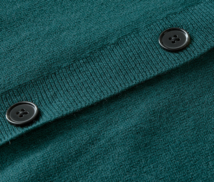 Gros plan sur un cardigan en tricot vert avec des boutons.
