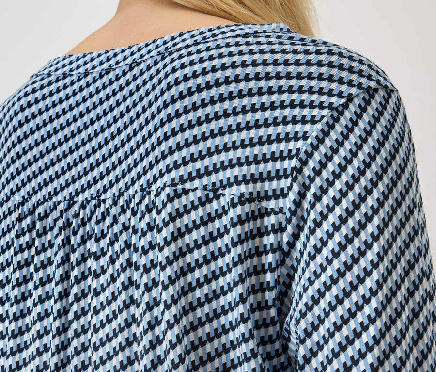 Vue arrière d'une femme blonde portant un chemisier pied-de-poule bleu et blanc.