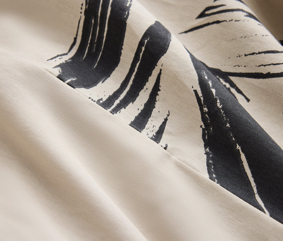 Gros plan d'un tissu crème avec un motif abstrait bleu foncé.