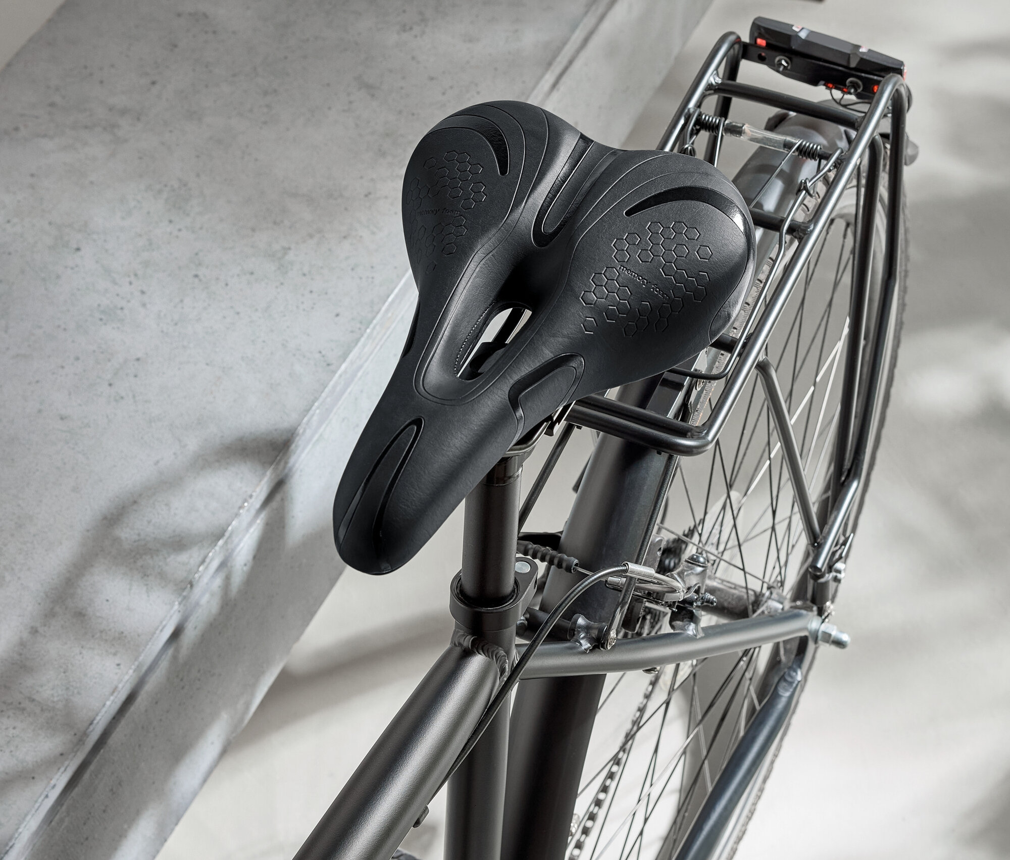 Vélo noir avec selle noire et casque noir sur une surface en béton.