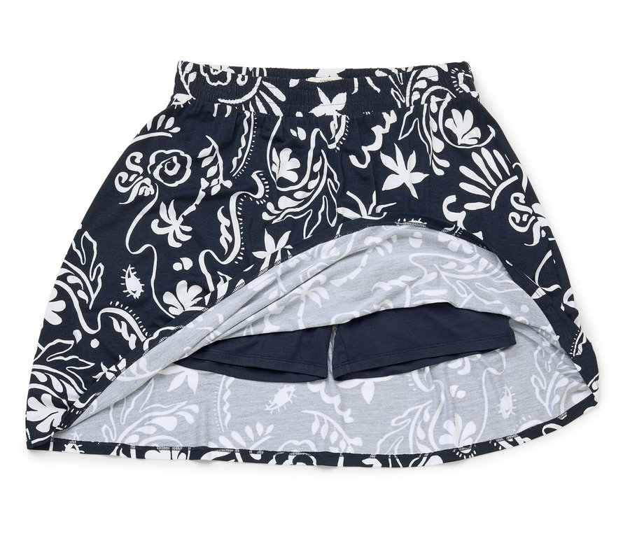 Une jupe bleu marine à motif floral blanc avec short intégré repose sur un fond blanc.