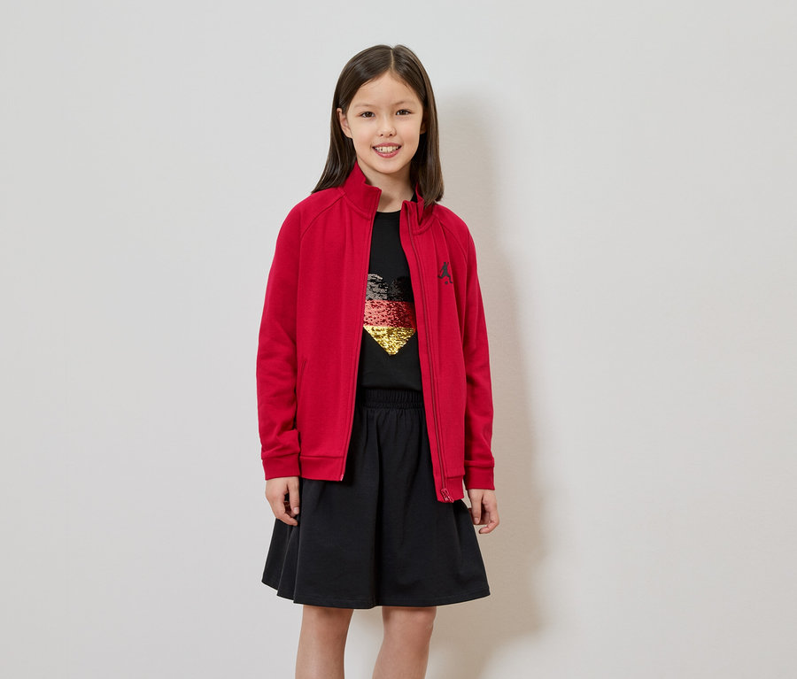 Fille en veste rouge, jupe noire et t-shirt avec un cœur allemand