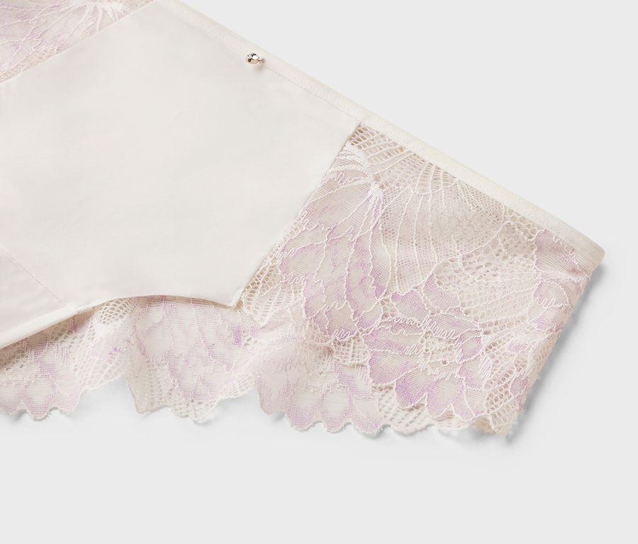 Gros plan d'un soutien-gorge blanc avec de la dentelle violette sur les bords sur fond blanc.