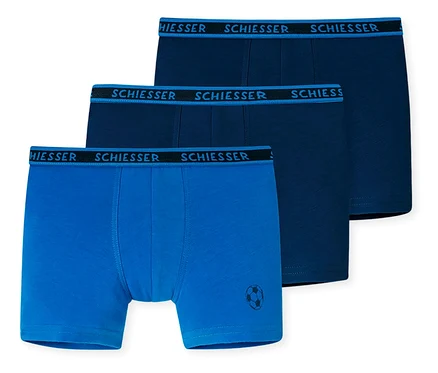 Trois boxers pour enfant SCHIESSER: deux bleu foncé et un bleu clair avec un motif de ballon de football sur la jambe.