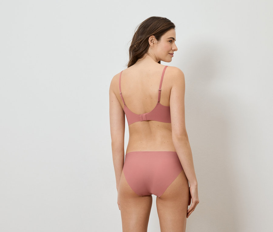 Femme vue de dos, portant un soutien-gorge rose et une culotte assortie.