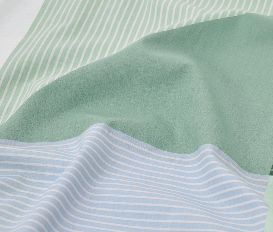 Gros plan sur du linge de lit bleu clair et vert à rayures.