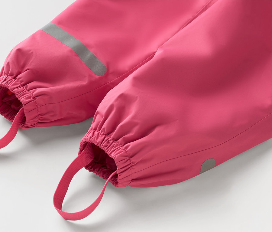 Gros plan d'un pantalon de pluie rose avec élastique et détails réfléchissants au bas des jambes.