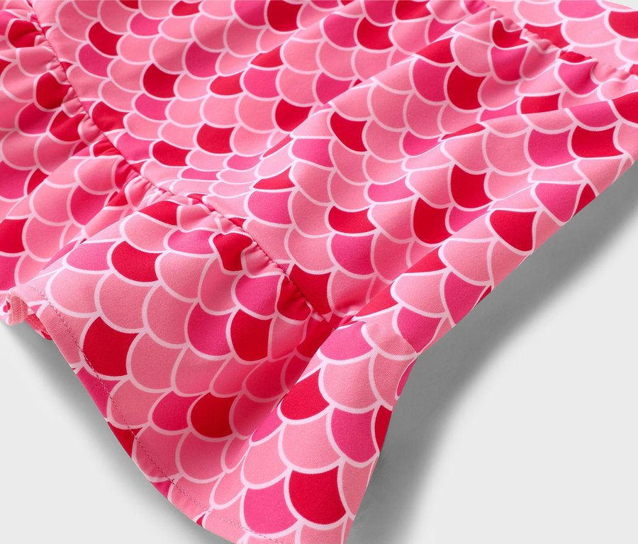 Gros plan d'un tissu rose à motif d'écailles de poisson.
