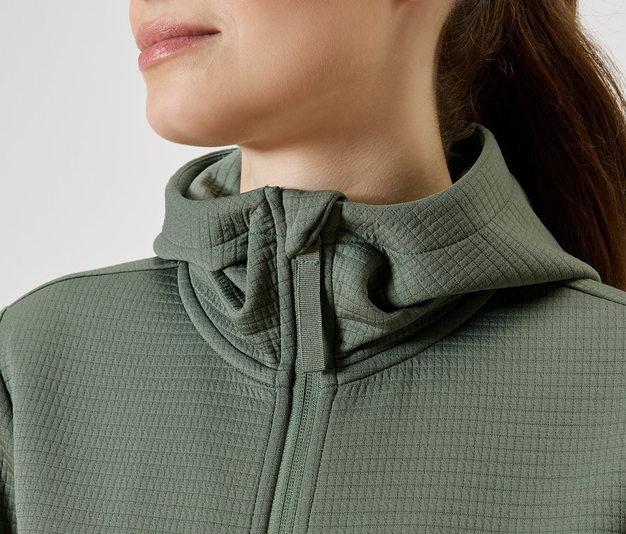 Gros plan d'une femme portant un sweat à capuche vert zippé.