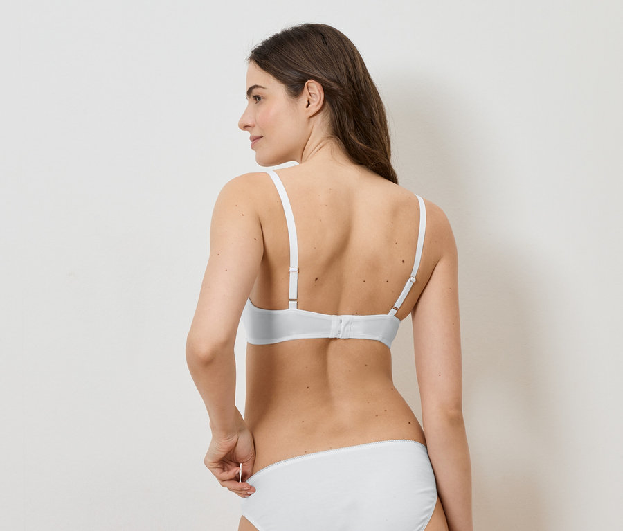 Femme vue de dos, portant un soutien-gorge et une culotte blancs, tenant la culotte sur le côté.