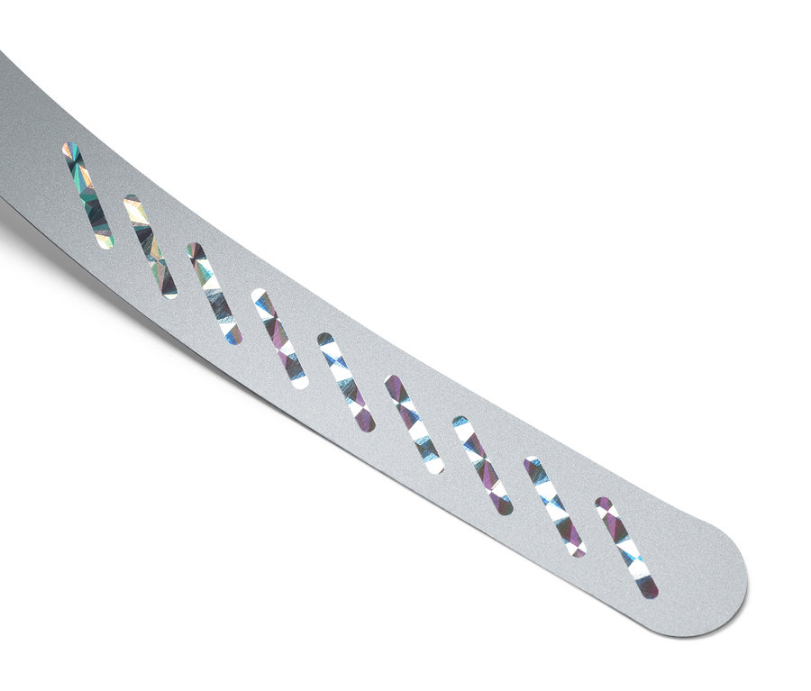 Gros plan d'un bracelet argenté avec des trous oblongs laissant entrevoir un motif coloré.