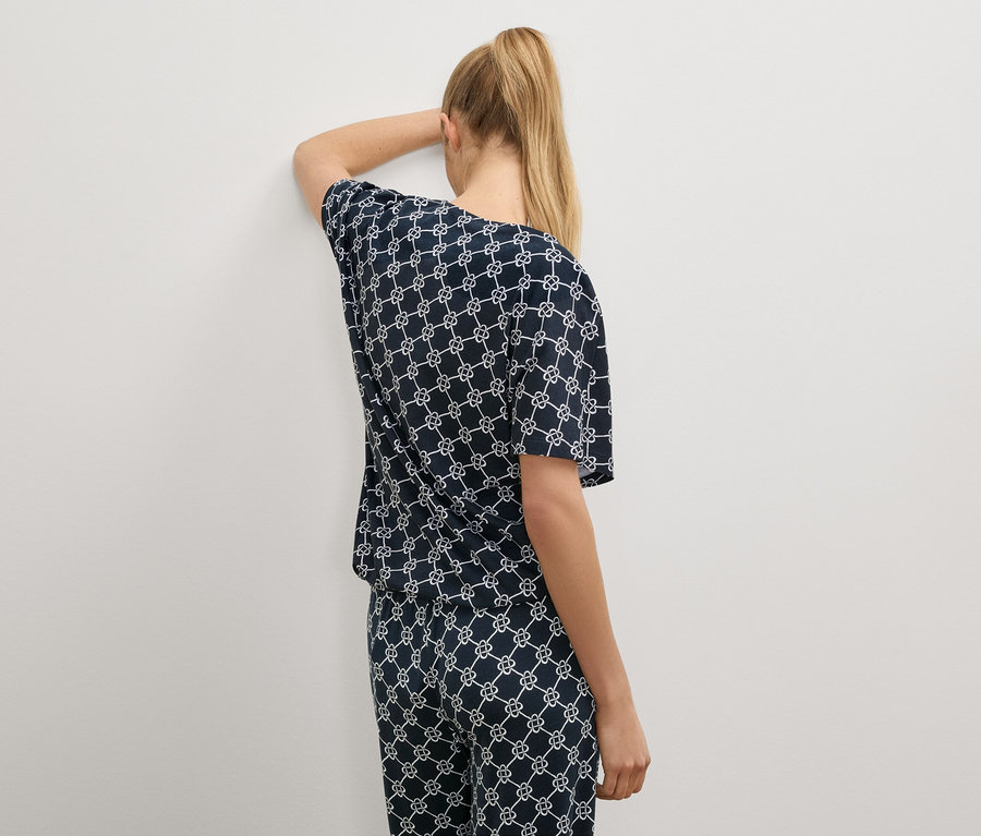 Une femme aux cheveux blonds porte un pyjama bleu marine avec un motif blanc.