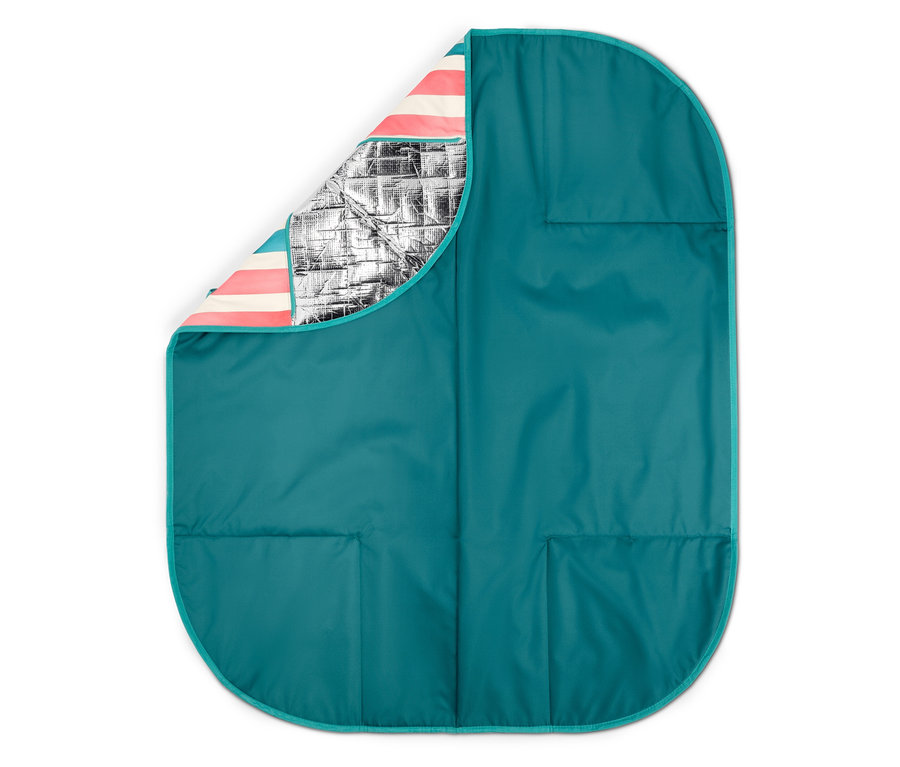Une couverture de pique-nique turquoise dépliée avec un coin replié révélant une doublure rayée et une isolation argentée.