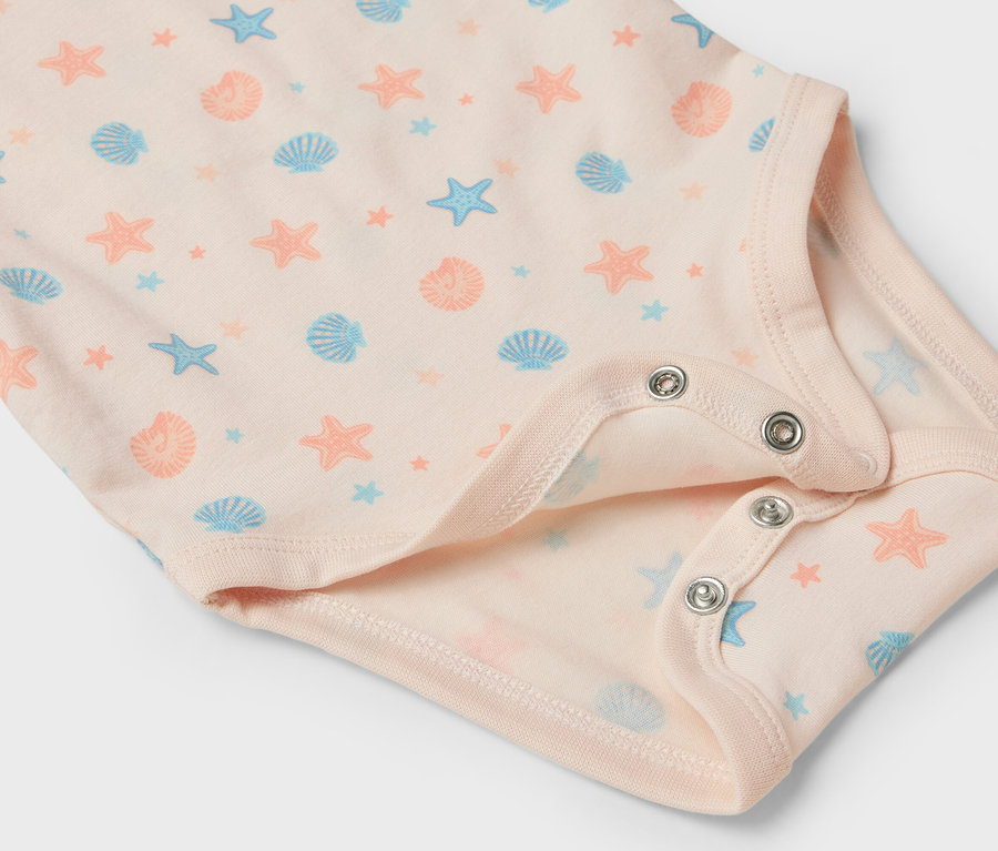 Vue détaillée d'un body bébé rose clair avec des motifs d'étoiles de mer et de coquillages.