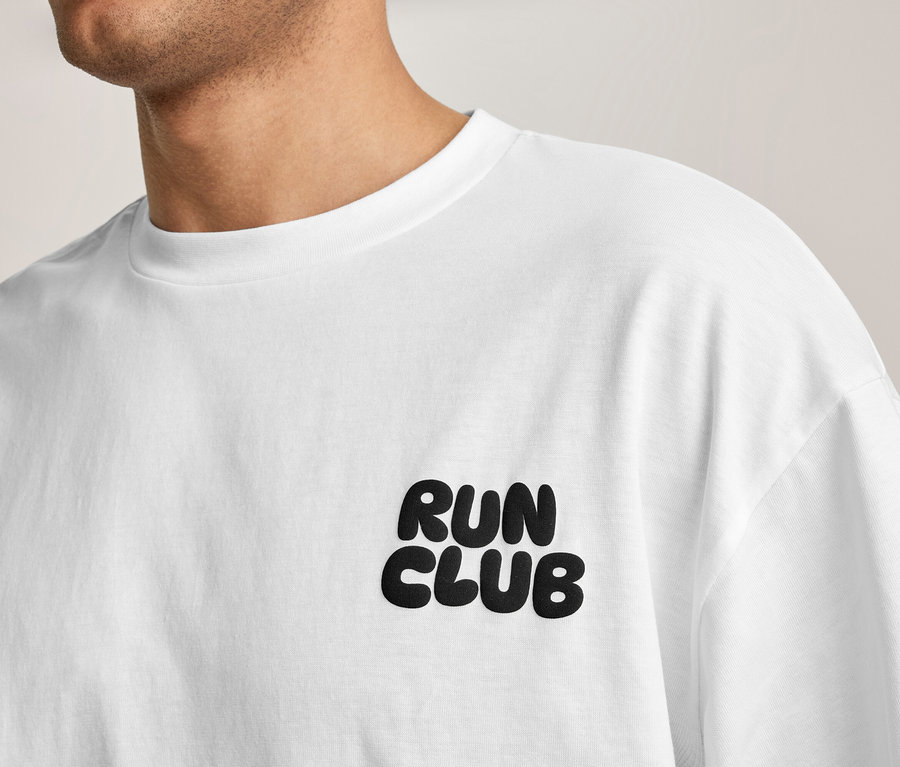 Une personne porte un T-shirt de sport blanc avec l'inscription « RUN CLUB » sur la poitrine.