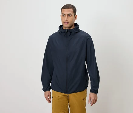 Un homme porte une veste à capuche bleu marine et un short doré.