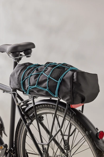 Un sac de vélo noir est fixé à un porte-bagages de vélo noir à l'aide d'un filet à bagages bleu.