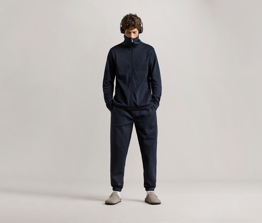 Homme portant un survêtement d’intérieur bleu marine avec des écouteurs.