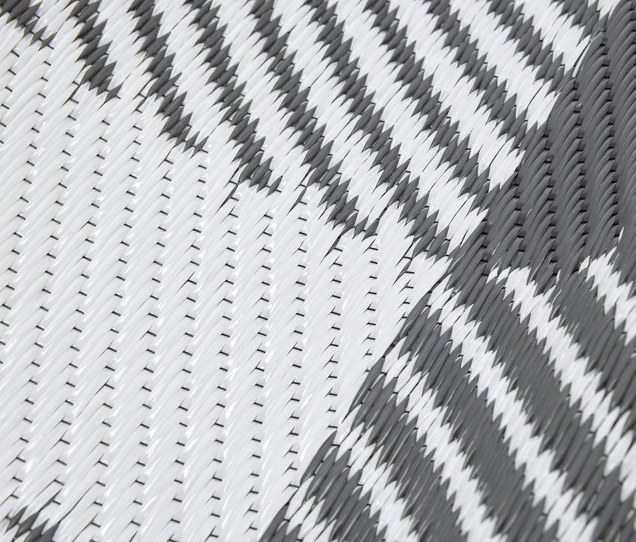 Gros plan d'un tapis tissé gris et blanc avec un motif en zigzag.
