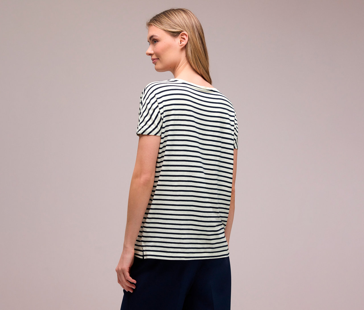 Femme vue de dos, aux cheveux blonds, portant un t-shirt Street One bleu marine et blanc à rayures horizontales.