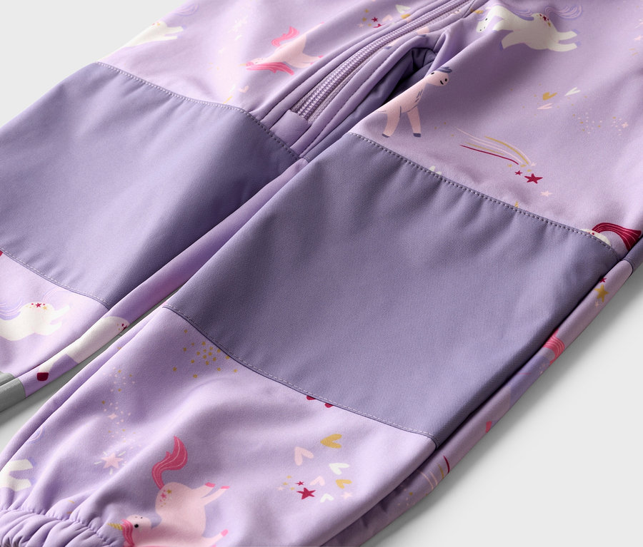 Gros plan sur une combinaison softshell violette avec des motifs de licornes et d'étoiles et une fermeture éclair intégrale.