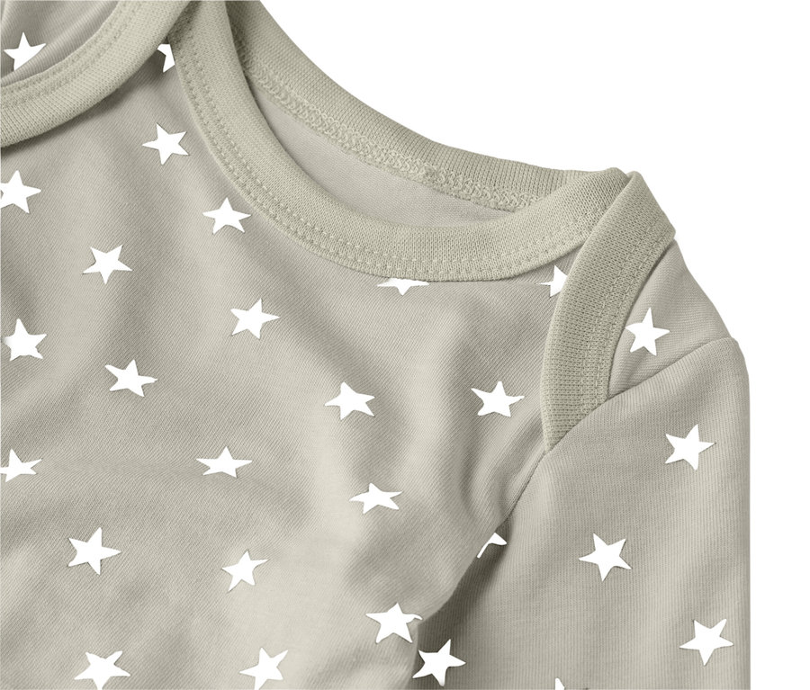 Gros plan sur un body de bébé marron clair avec des étoiles blanches.