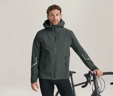 Homme en veste à capuche vert foncé avec des bandes réfléchissantes, debout à côté d'un vélo et tenant le guidon.