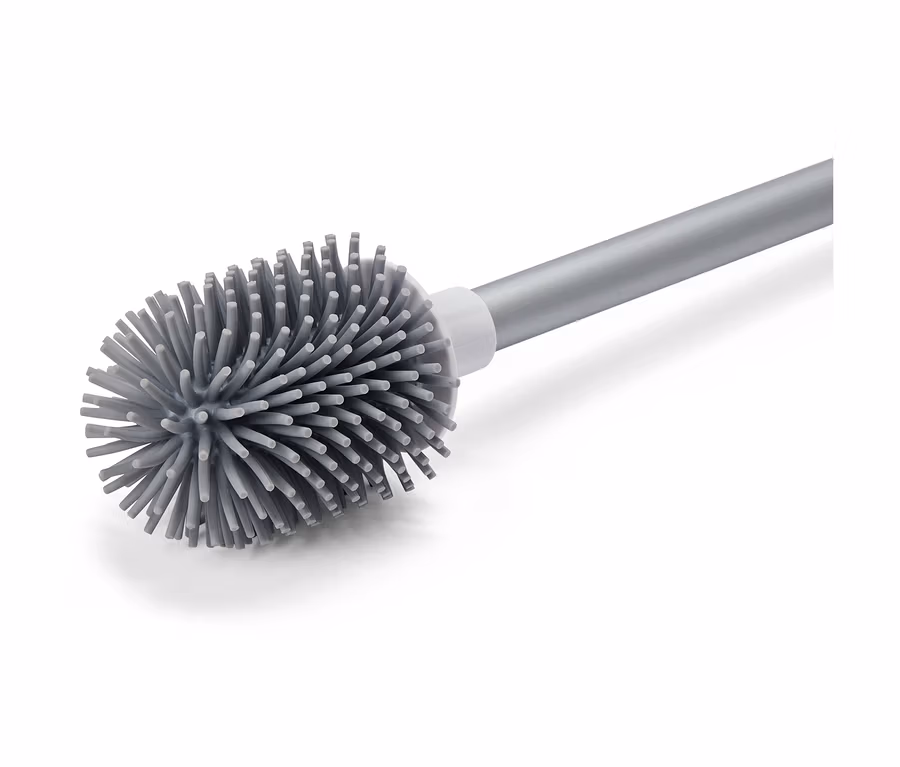 Une brosse de toilette grise avec un manche argenté est disposée en diagonale sur un fond blanc.