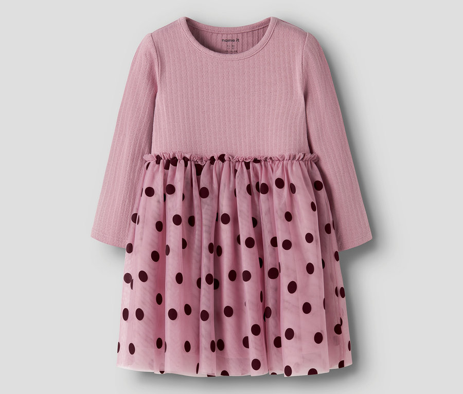 Robe rose à manches longues avec un haut côtelé et une jupe transparente à pois foncés. La taille est froncée.