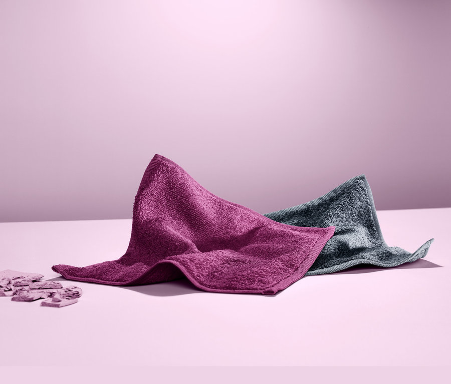 Deux lingettes démaquillantes sont posées côte à côte sur une table. L'une est violette et l'autre grise.