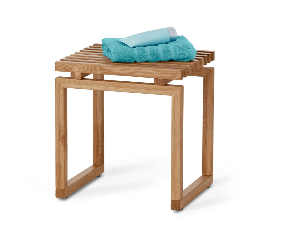 Un tabouret en bois sur lequel reposent une serviette turquoise et un tube bleu clair.