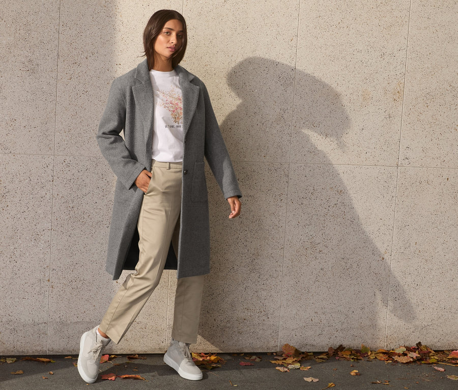 Femme posant en manteau gris.