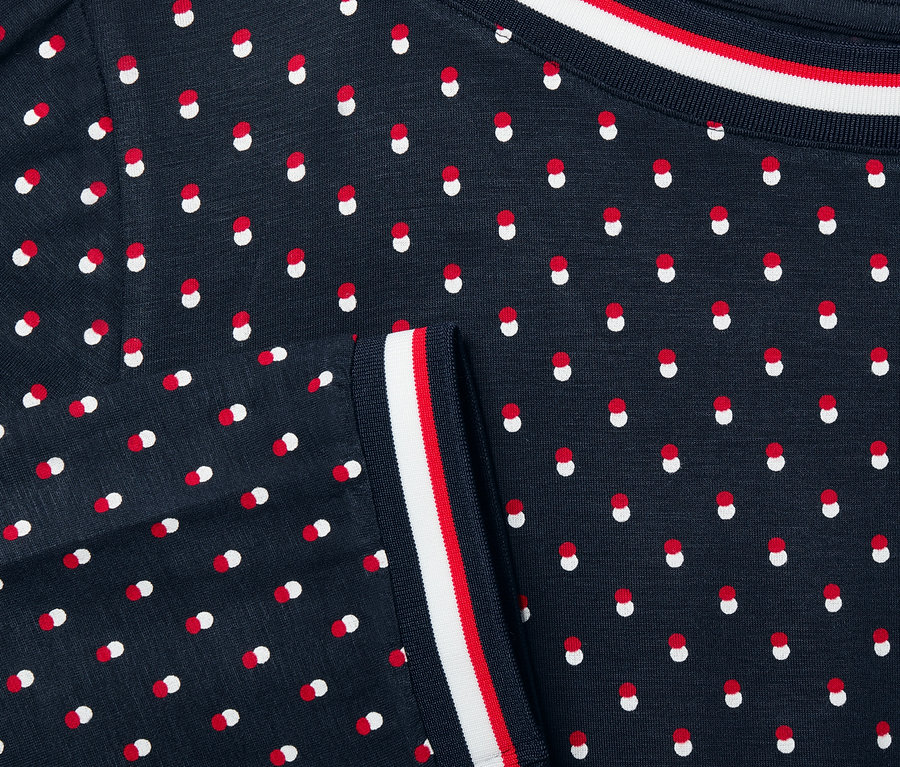 Gros plan sur une blouse marine à pois rouges et blancs et manches 3/4.