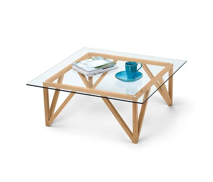 Table basse avec plateau en verre, magazines et tasse.
