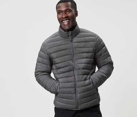 Un homme souriant pose en veste matelassée à ranger grise.