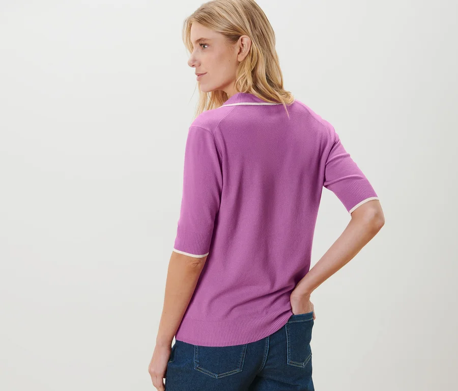 Femme posant en jean et polo en maille fine violet.