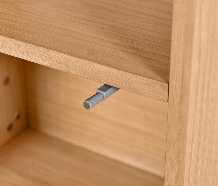 Gros plan d'une armoire de salle de bain avec placage bois et mécanisme gris.