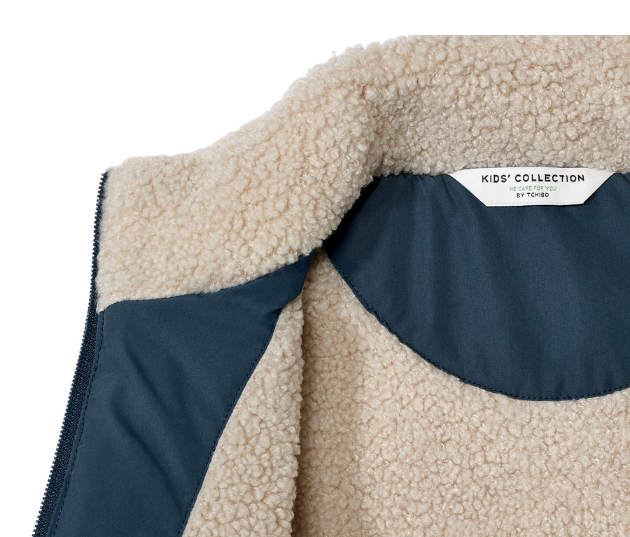 Détail d'un gilet sans manches matelassé en teddy pour enfant, intérieur bleu.
